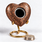 De laatste aai hartvormige mini urn in koperkleur met zwart patroon op een goudkleurige standaard