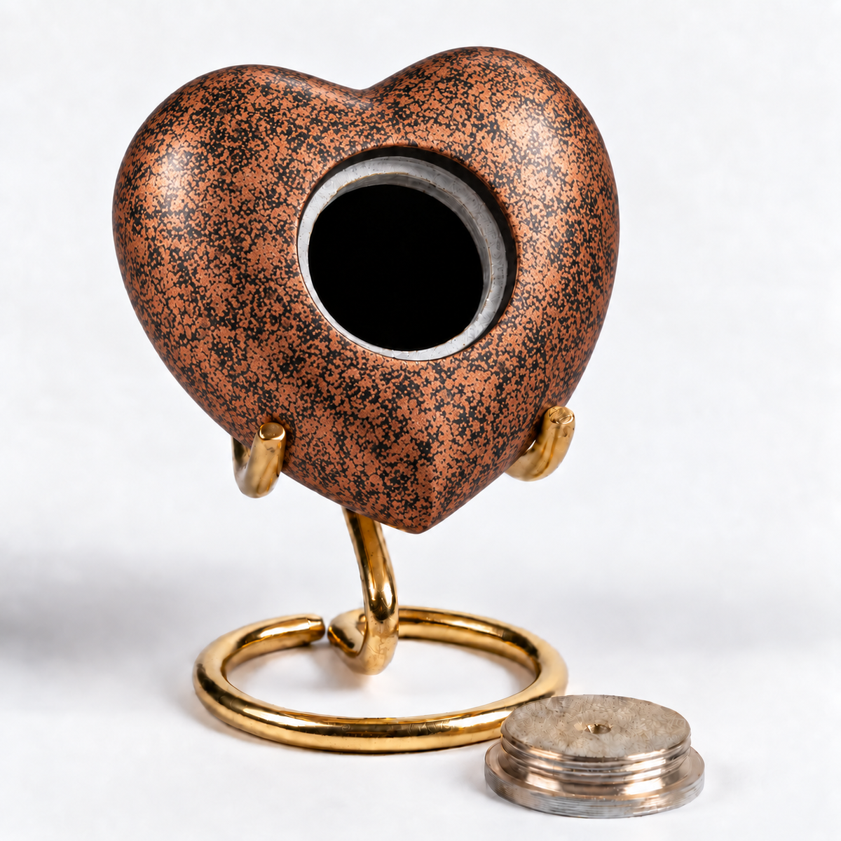 De laatste aai hartvormige mini urn in koperkleur met zwart patroon op een goudkleurige standaard