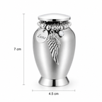 De laatste aai zilverkleurige RVS mini urn met naamplaatje, engelenvleugel bedel en afmetingen van 7 bij 4,5 cm.