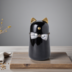 De laatste aai zwarte keramische kattenurn met gouden oortjes en een decoratief strikje op een houten ondergrond