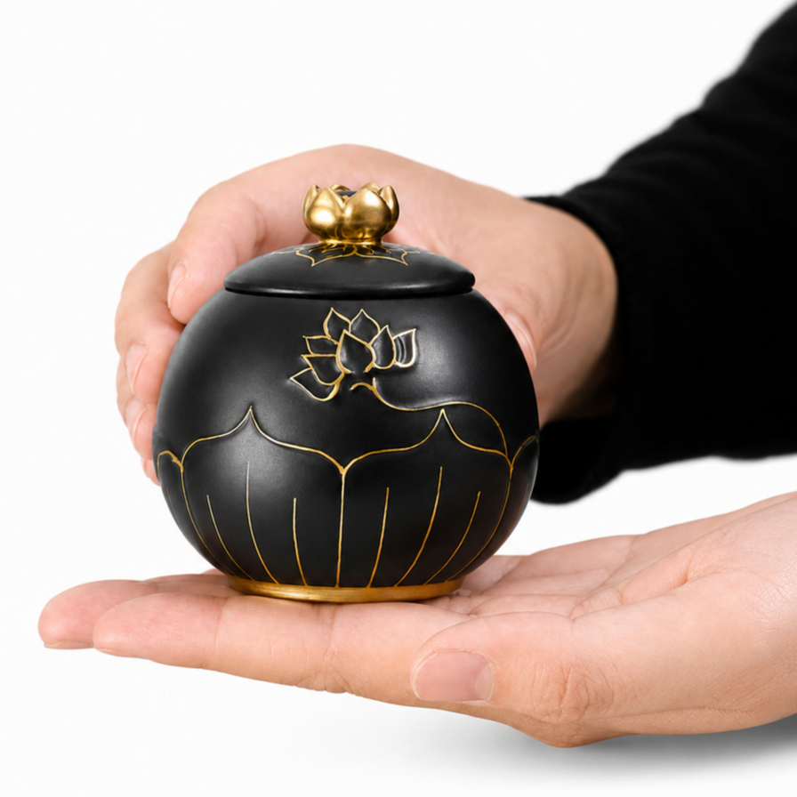 De laatste aai zwarte keramische lotus urn met gouden details, vastgehouden in twee handen als aandenken aan huisdier.